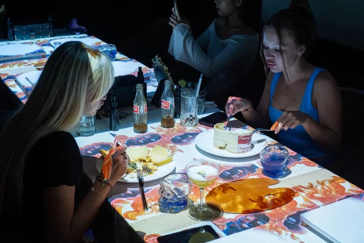 Guests enjoying interactive projection dining experience at a Bali restaurant with animated visuals on the table.