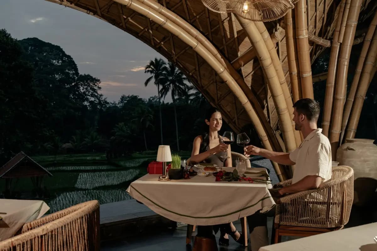 Couple enjoys a private candlelit dinner overlooking Bali rice fields, perfect for a romantic luxury dining experience.