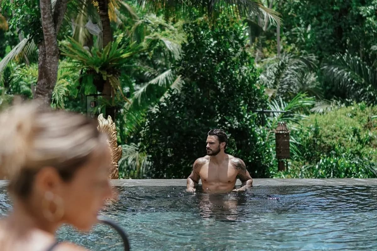 Guest relaxes in an infinity pool surrounded by tropical greenery, showing the peaceful atmosphere of Ubud pool escapes.