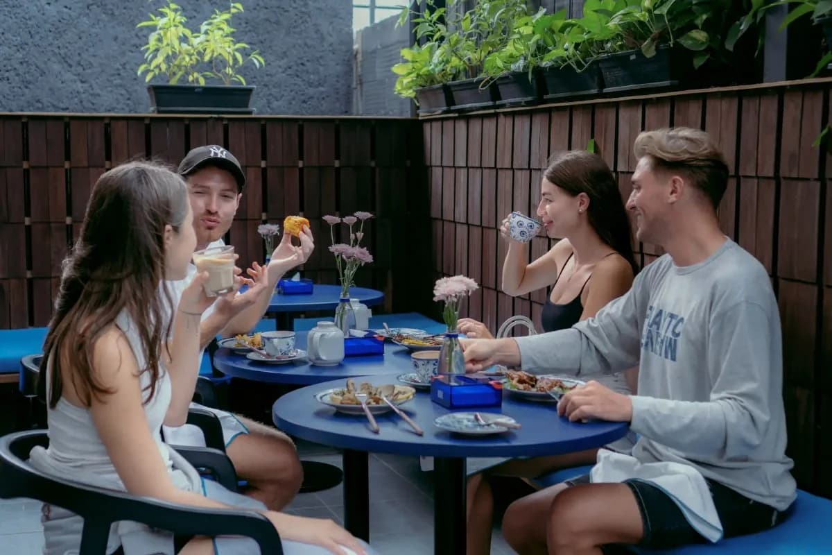Friends enjoy breakfast together outdoors at a casual cafe in Canggu, with food, drinks, and conversation.
