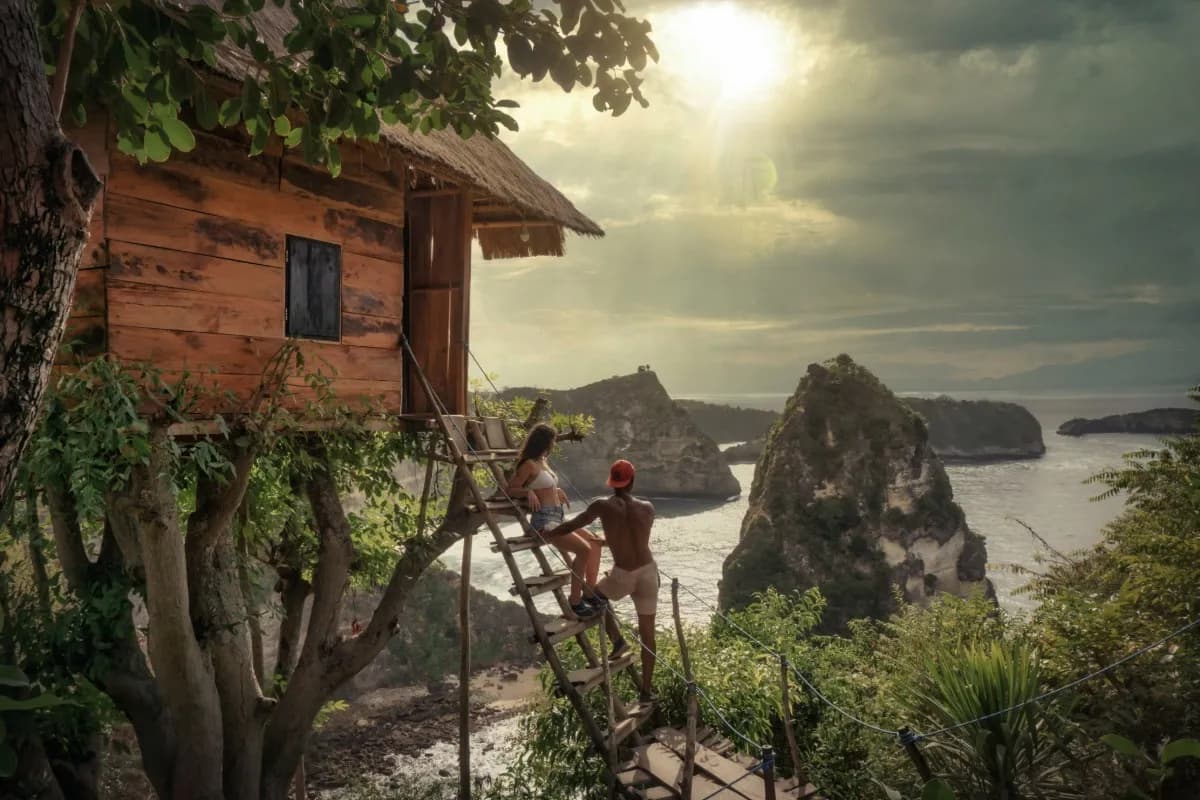 Travelers sit outside a wooden hut overlooking Bali’s rocky coastline, illustrating a scenic stop during solo travel.