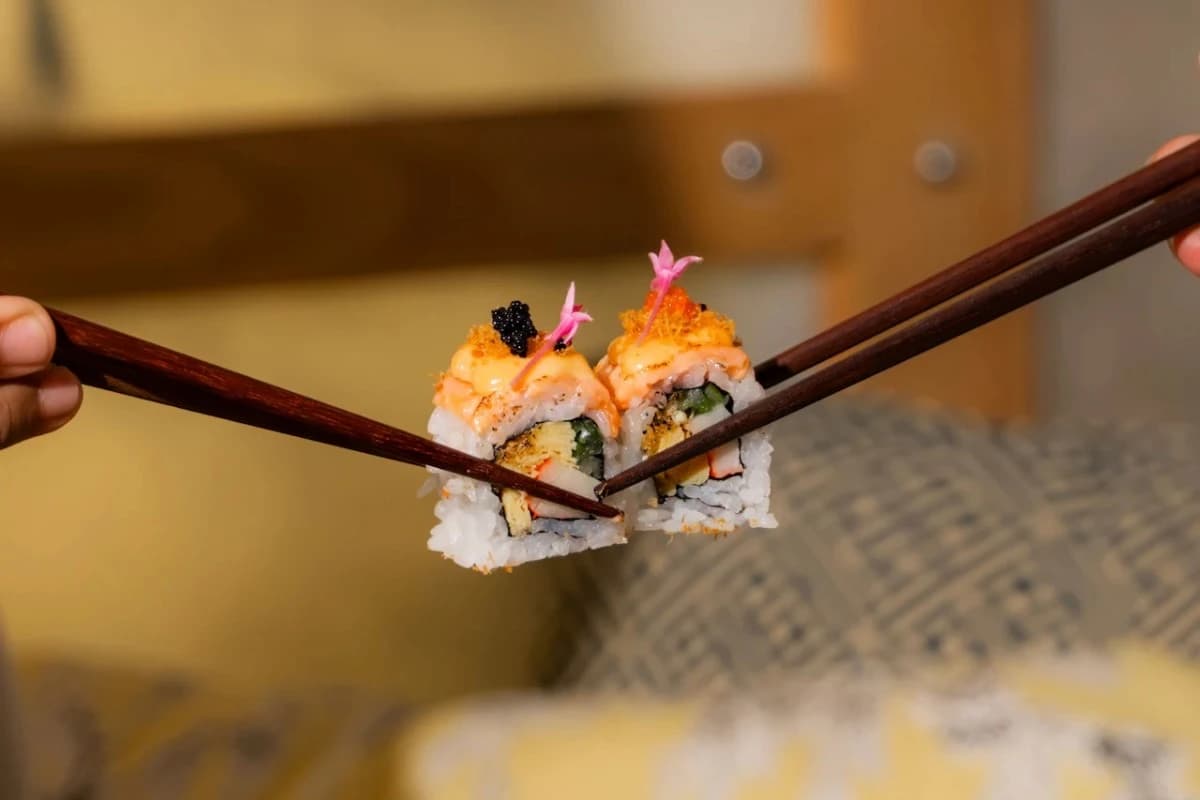 Sushi rolls held by chopsticks, showing a dining experience at a sushi restaurant in Bali.