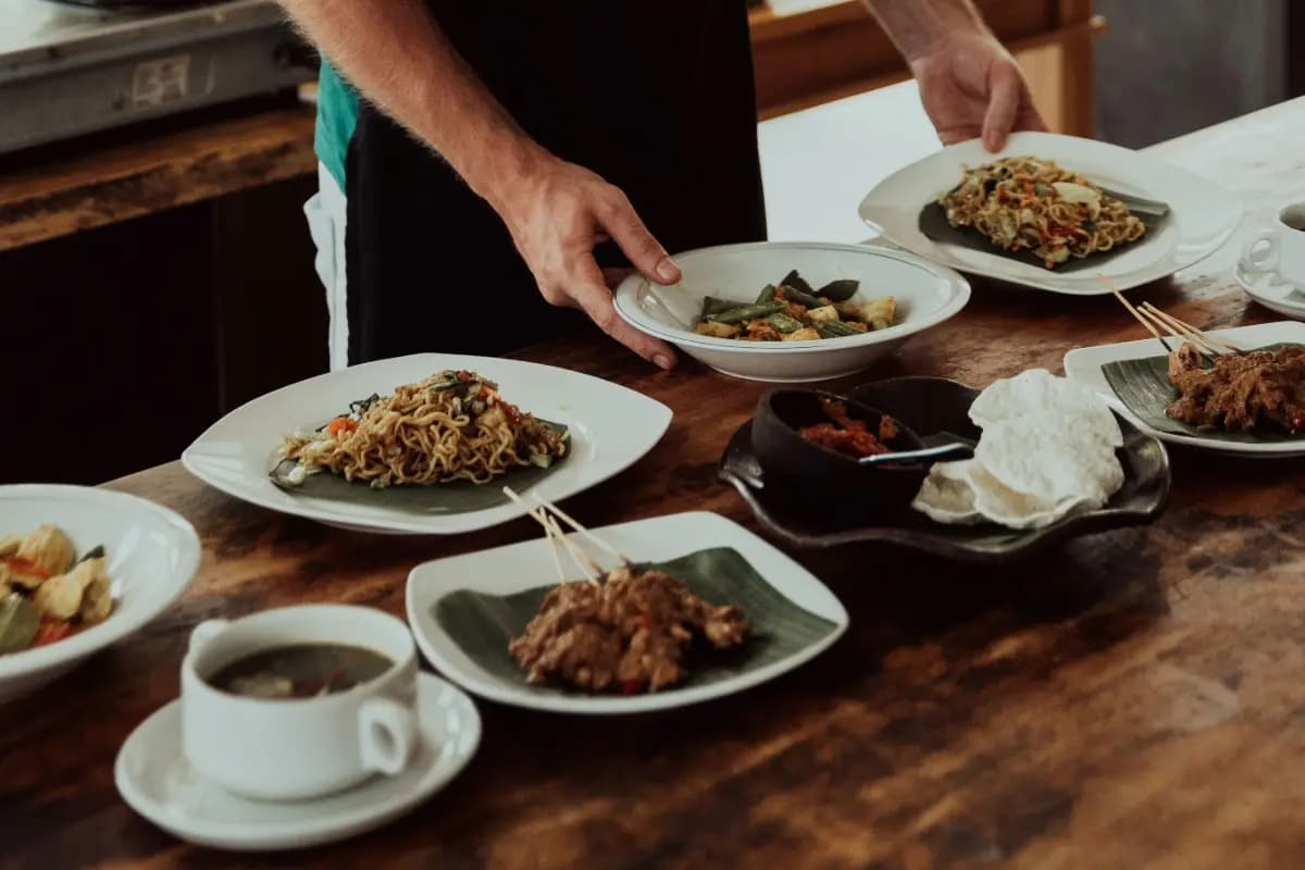 Several Balinese dishes are served on a wooden table, showing the variety of meals found across Bali.