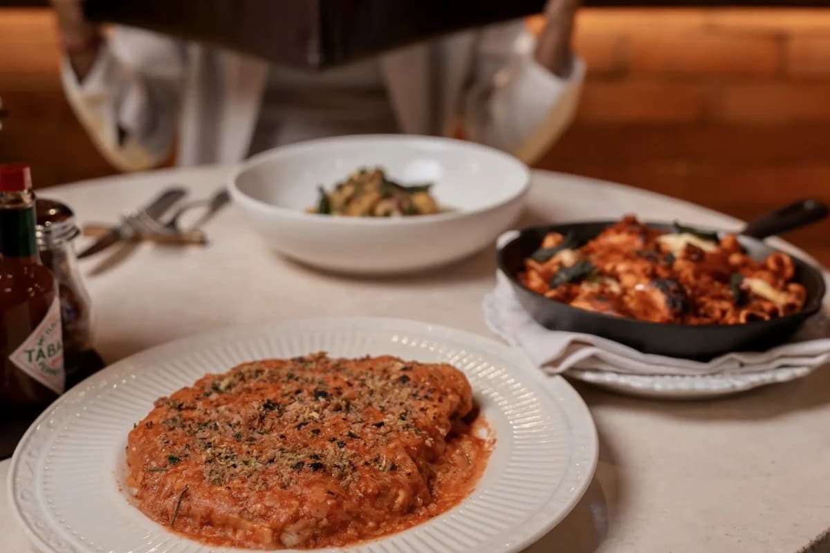 Italian dining table in Canggu featuring a baked pasta dish, pizza, and another pasta dish for sharing.