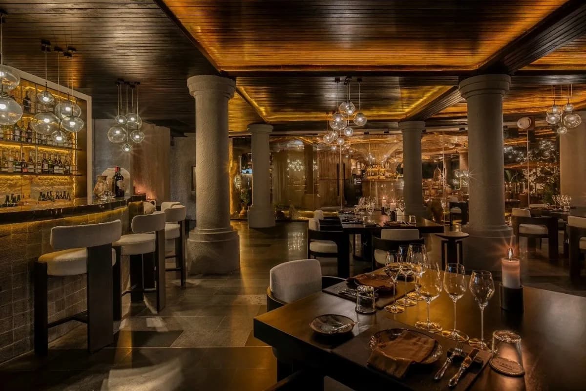 Elegant Ubud restaurant interior with a bar, wine glasses, candlelit tables, and warm wooden lighting for steak dinners.