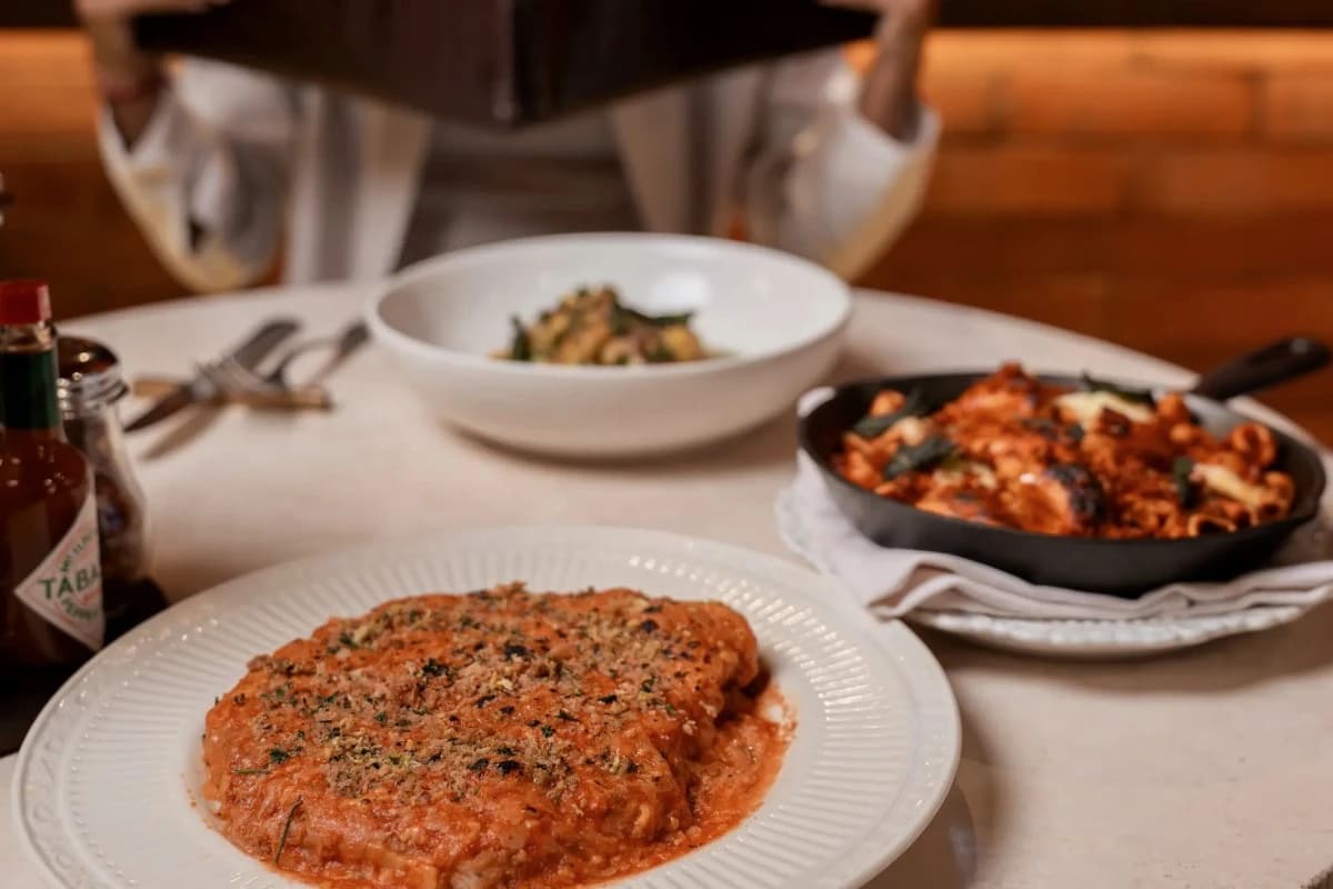 Italian pasta with tomato sauce and herbs served alongside another pasta dish at a restaurant, illustrating Italian dining at Cantina Classe in Canggu.